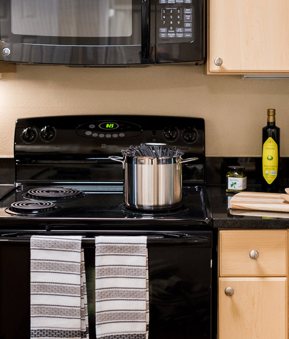 close up of black updated kitchen stove with light wood cabinets surrounding appliances