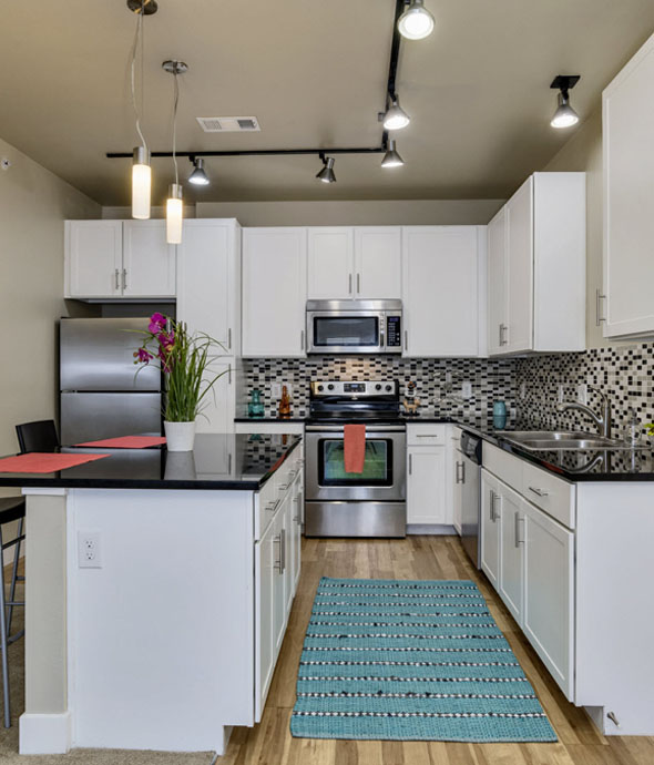 modern kitchen with studio lights sleek black countertops, white cabinets, and stainless steel appliances