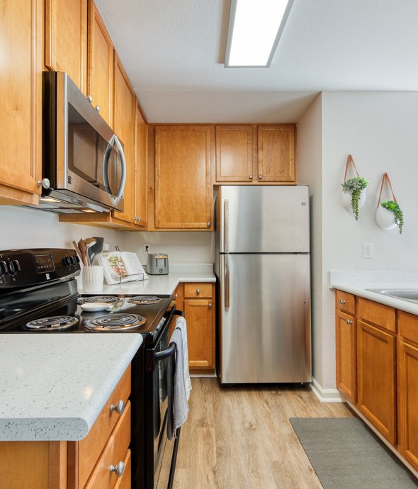 Apartment kitchen with hardwood floors, and stainless steel appliances, sleek granite countertops