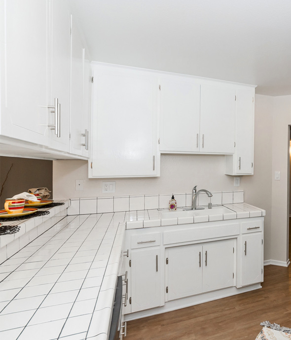 IMT Valleyheart - kitchen area with modern white tile countertops and white cabinets on hardwood floors