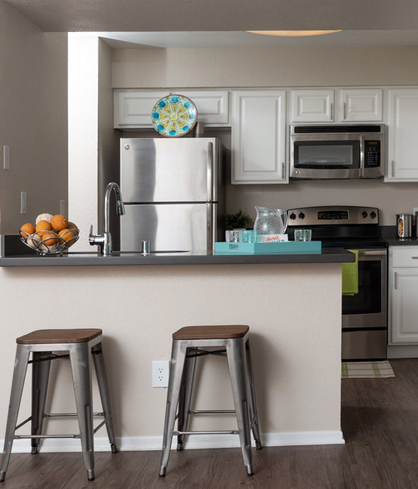 IMT Wood Ranch - modern apartment kitchen with stainless steel appliances and bar counter with steel bar stools