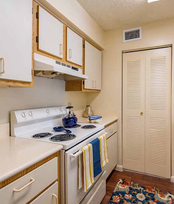 Kitchen with tan counters and cabinets and white electric range.