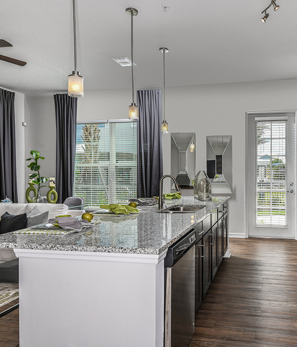 Kitchen with wood floor, marble counters, pendant lights, large windows and door to balcony.