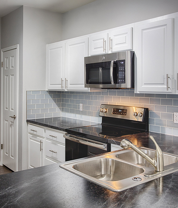 Kitchen with dark counters, white cabinets, and stainless steel appliances.