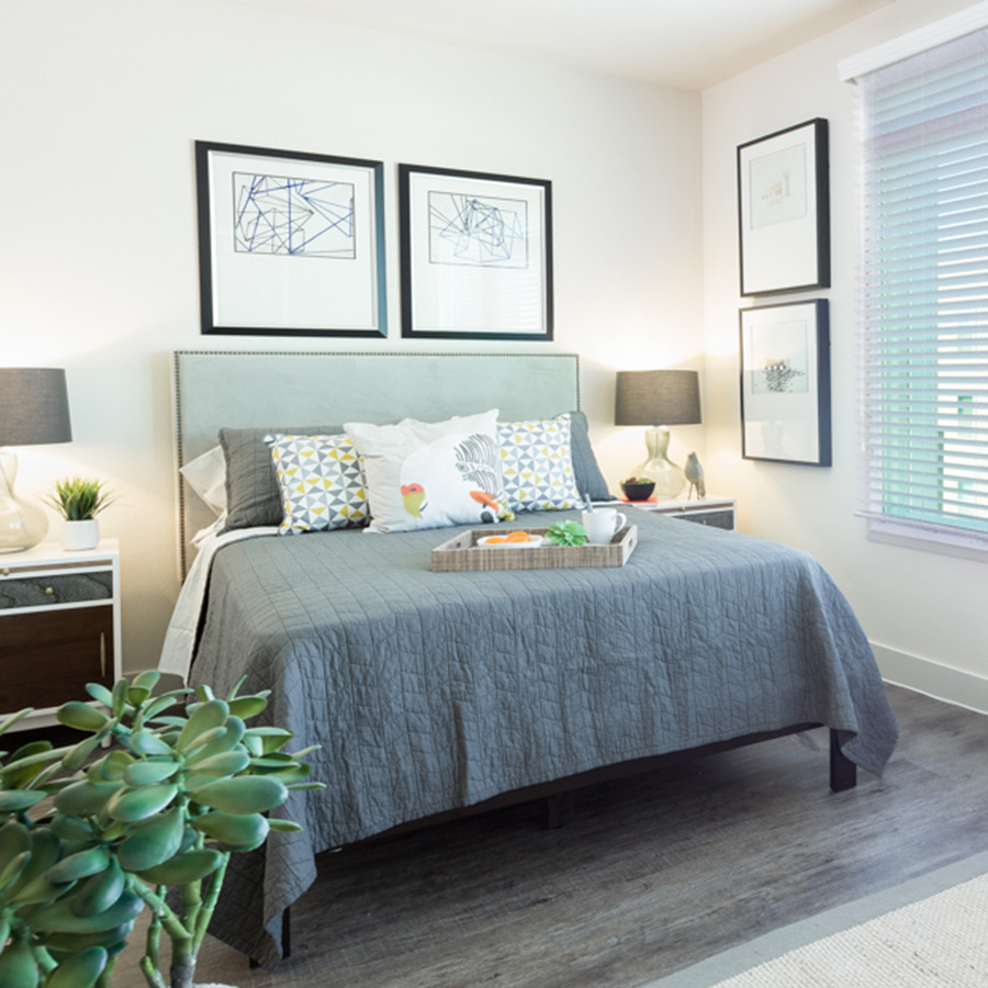 Bedrom with large platform bed with plush bedding and platter with food, wall art, and large window with natural light.