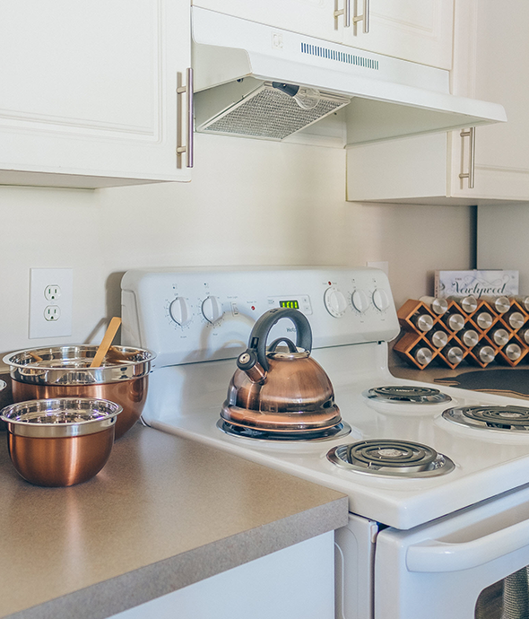Kitchen with white appliances, wood cabinetry, and grey countertops