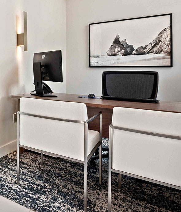 Business Center with desk, computer, two chairs, and a picture on the wall