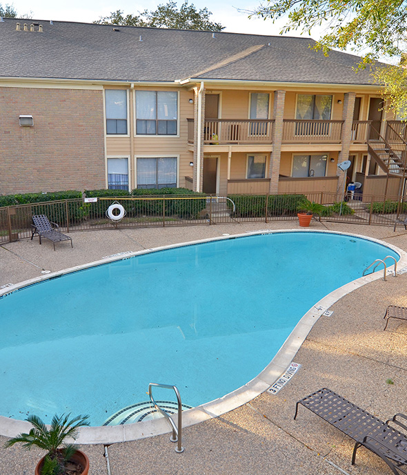 IMT Pavilion Place - Fenced pool area with curved pool, stone paver patio, and lounge chairs.
