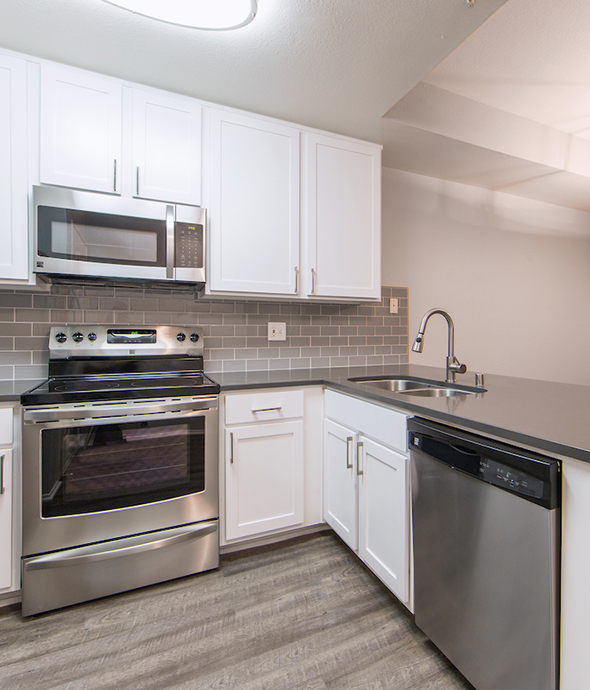 IMT Stevenson Ranch - Kitchen with wood floors, white cabinets, dark counters and stainless steel appliances.