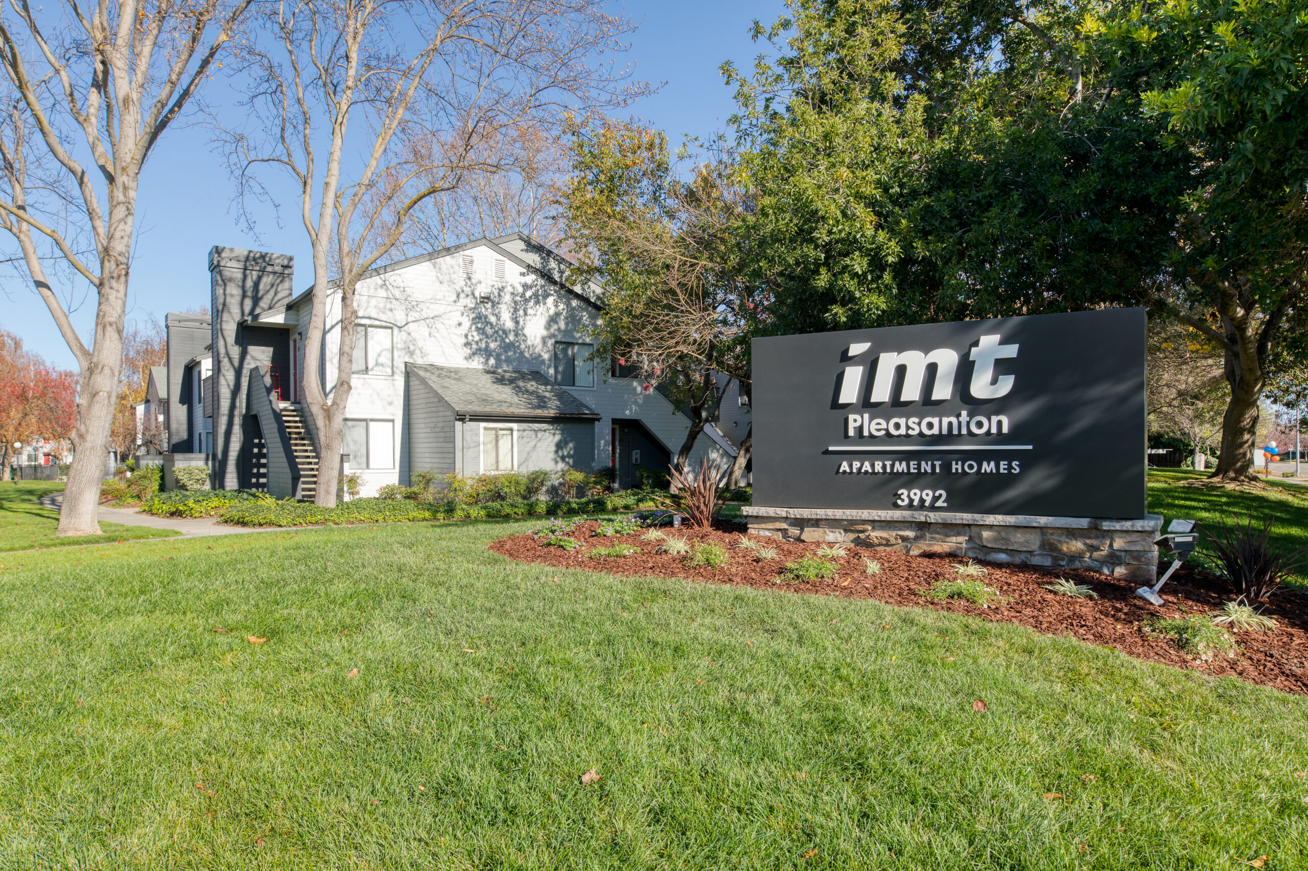 IMT Pleasanton - Sign in front of buildings, greenery, apartments in the background