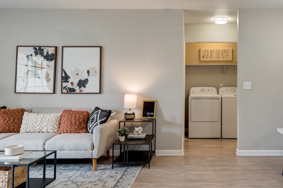 IMT Ahwatukee - Model Home living room area with neutral décor and view of laundry room.