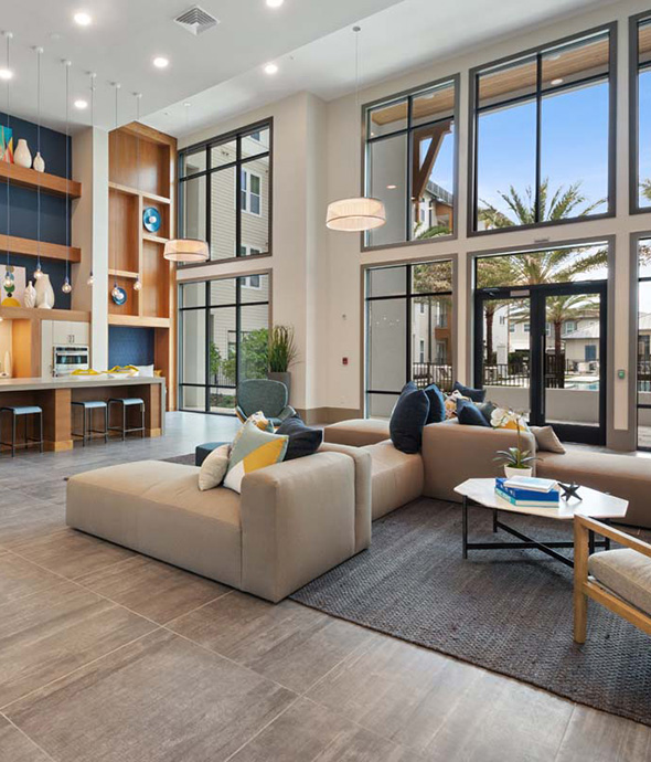 Clubhouse kitchen with lounge chairs, stainless steel appliances, and large windows.