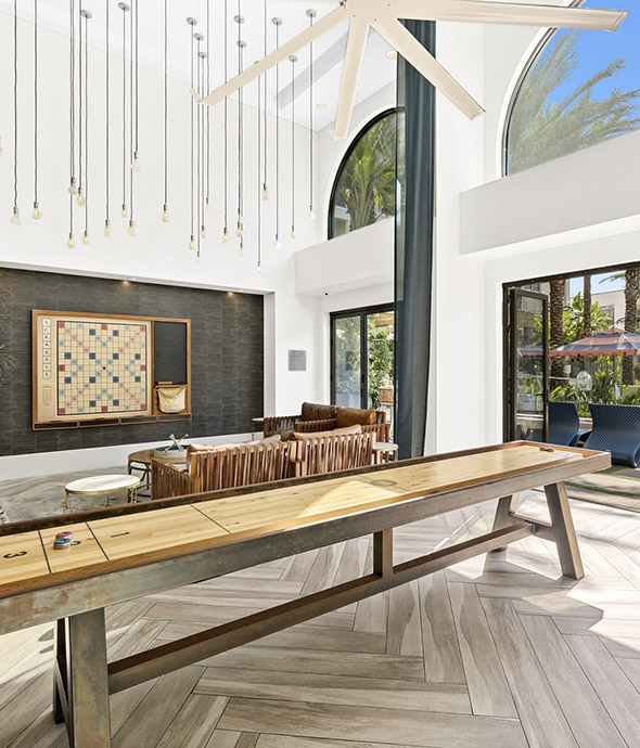 Game room with vaulted ceilings, shuffleboard, scrabble, and large doors.
