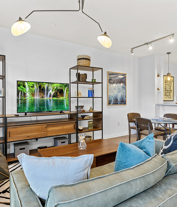 Living area with plush seating, shelves with decor, and dining table.