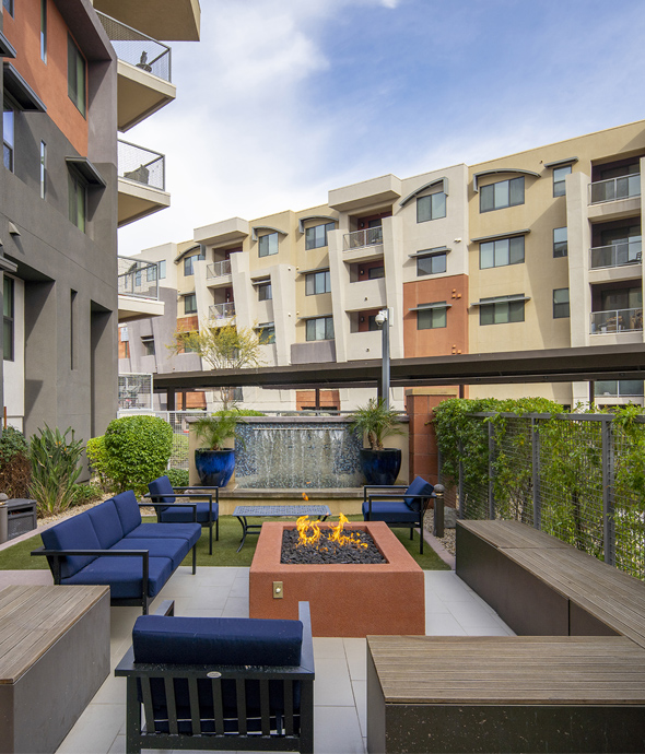 Outdoor lounge with firepit, plush seating, and lush landscaping.