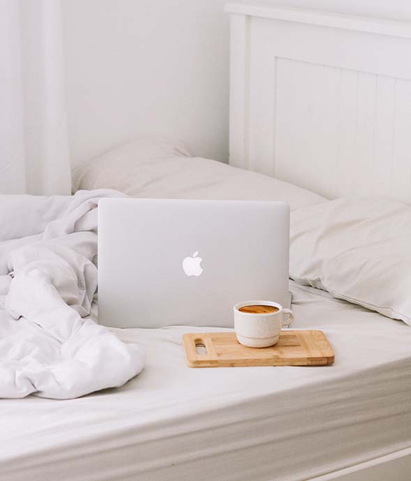 Plush bed with coffee mug and laptop computer.